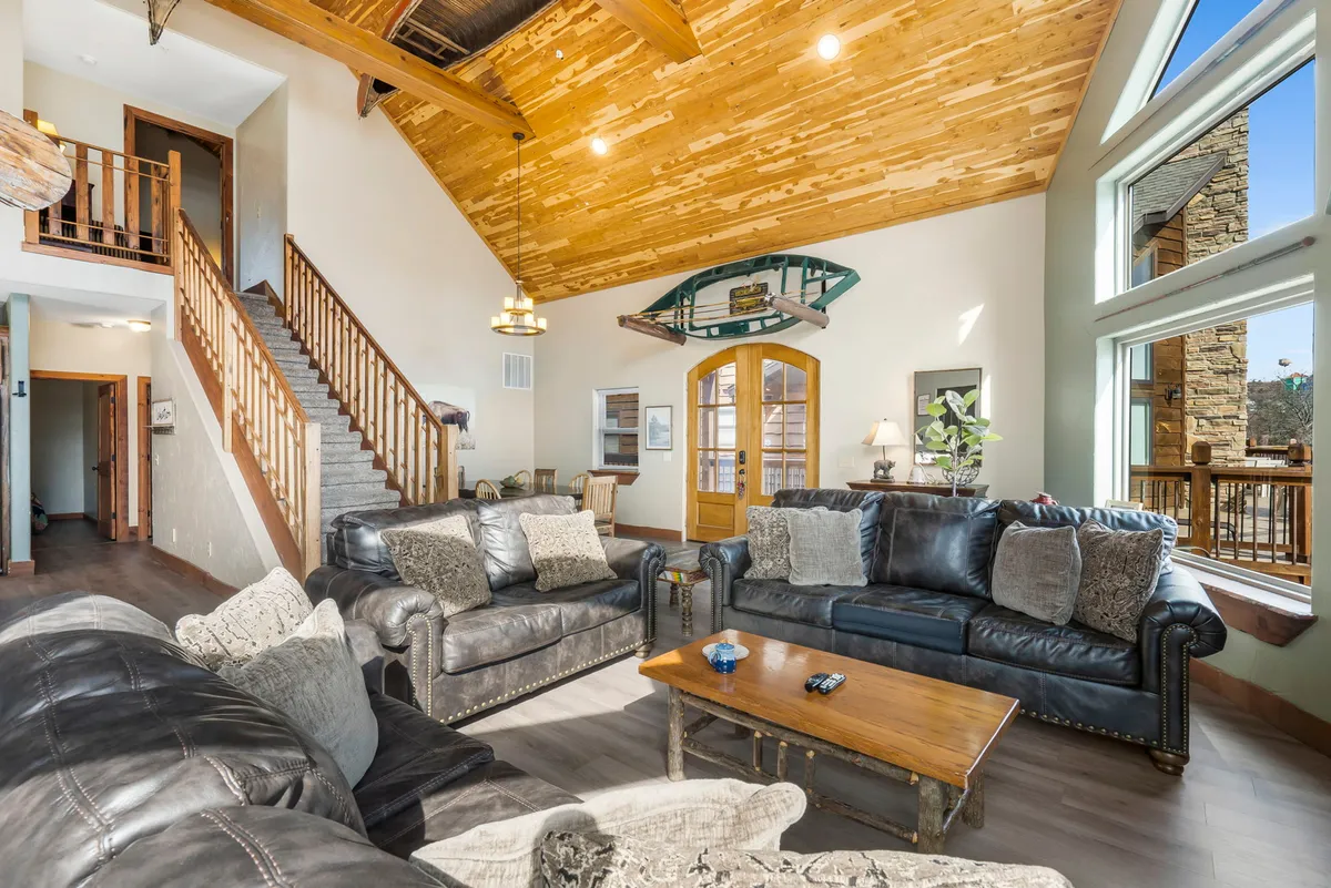 A cozy living area with comfortable leather sofas, a decorative boat on the wall, large windows letting in natural light, and a wooden coffee table perfect for games or snacks. The space conveys warmth and opportunities for relaxation or playful gatherings.