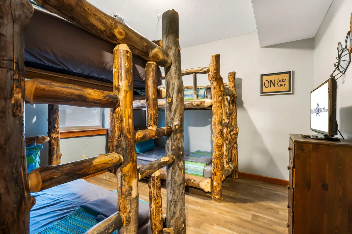 A fun and playful bunk room with wooden bunk beds, cheerful bedding, and a TV. The space is designed for younger guests, offering an inviting, camp-like atmosphere perfect for group fun and sleepovers.