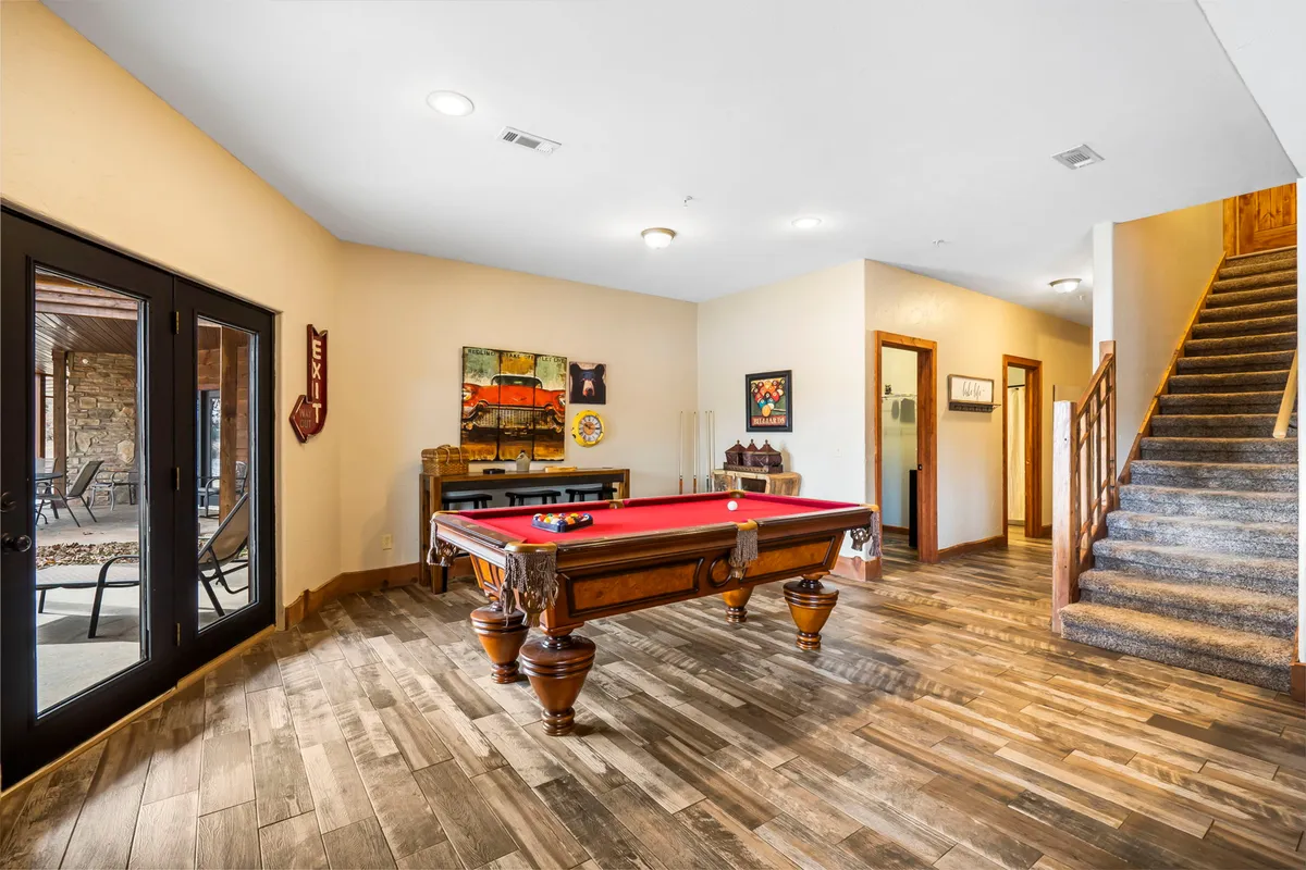 This interior image centers on a stylish entertainment lounge with a pool table as the main feature. Art decorates the walls, and a staircase adds architectural interest. The space is open, well-lit, and designed for socializing and play.
