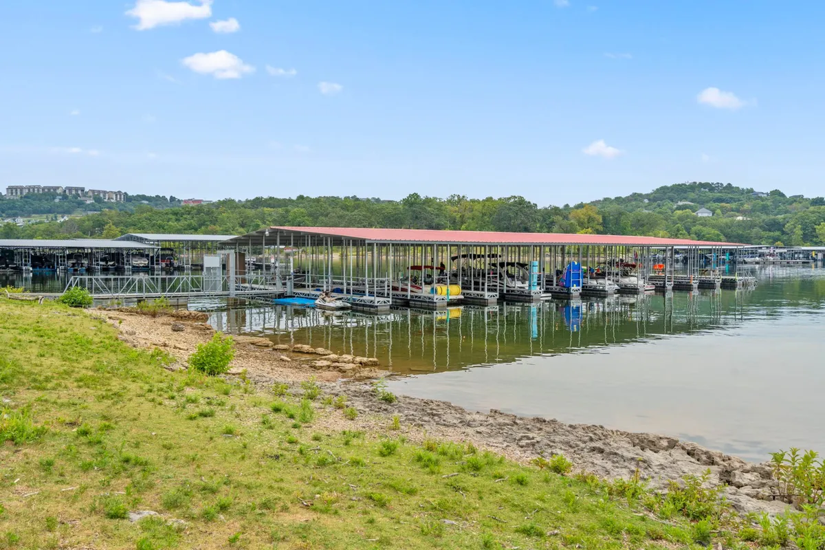 A serene lakeside scene featuring boat docks, boats on the water, and rolling hills in the distance. The tranquil setting is ideal for boating, fishing, and lakeside picnics, and the calm water reflects the sky, highlighting natural beauty.